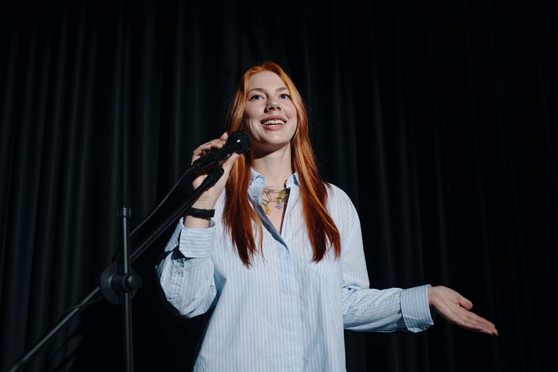 Portrait of Woman Holding Microphone on Stage Smiling