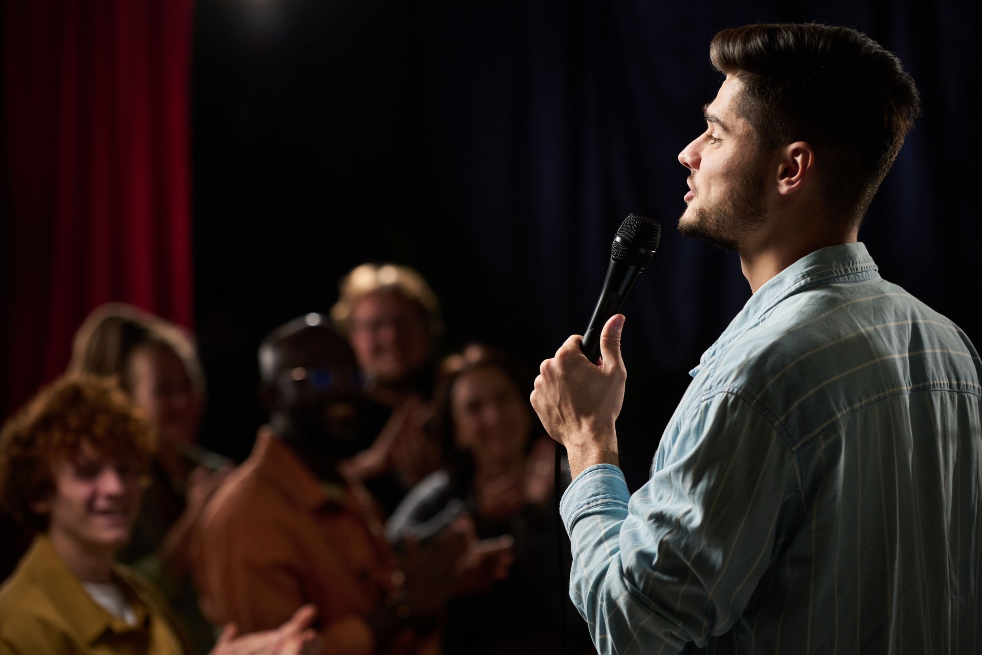 Man Singing on Stage in Front of Audience with Microphone